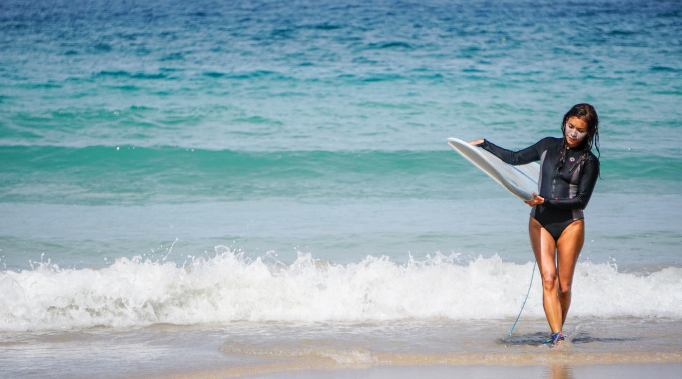 Female surfer wearing a sharkskin one piece step in suit